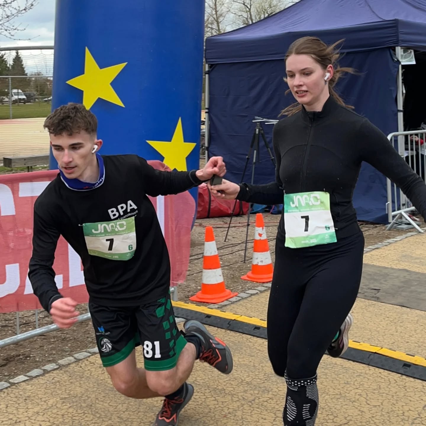 Dva běžci v dresu BPA předávají štafetu během Juniorského maratonu v Pardubicích.